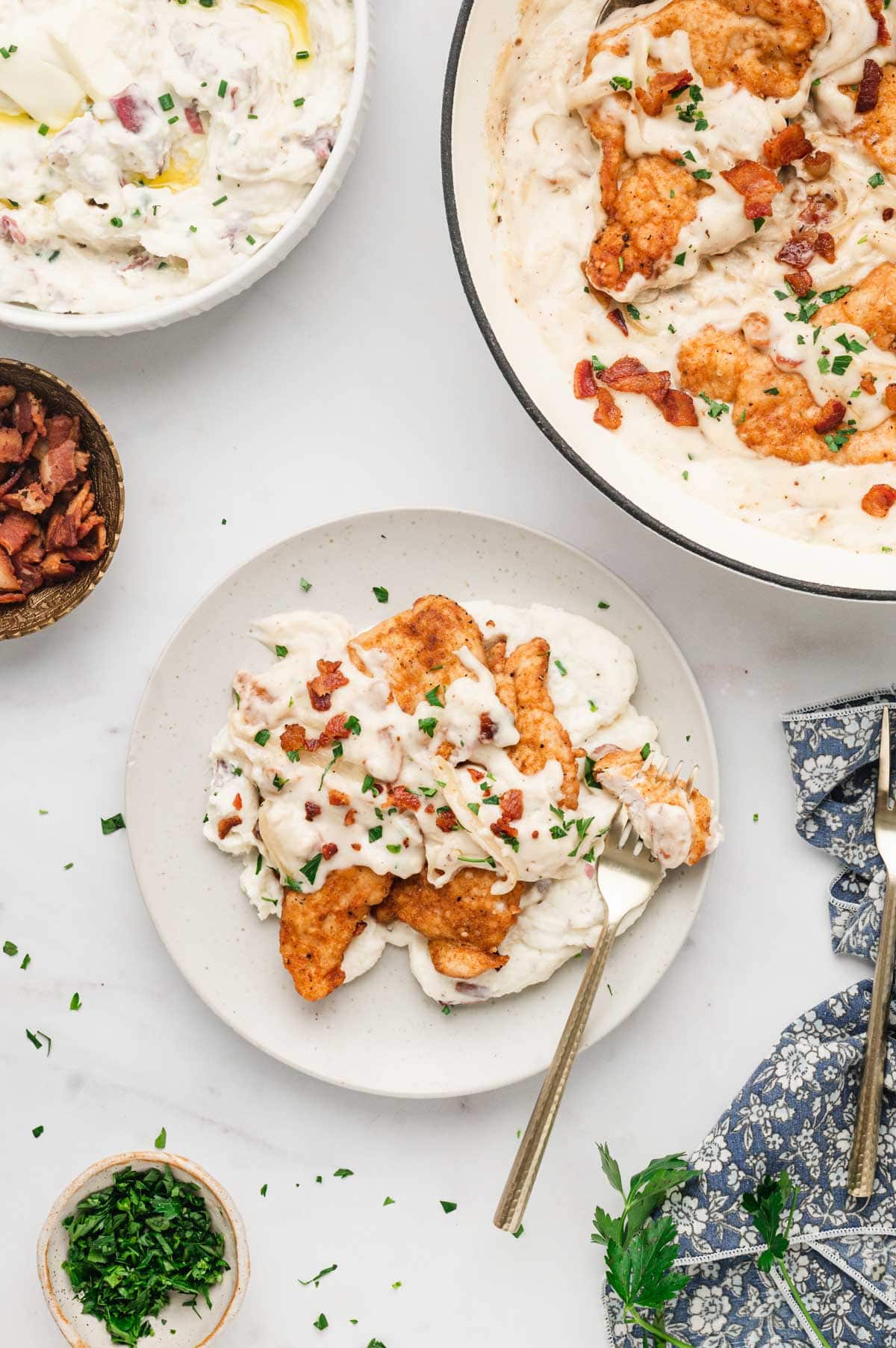 Plate with mashed potatoes and pan fried chicken with bacon and onion gravy.