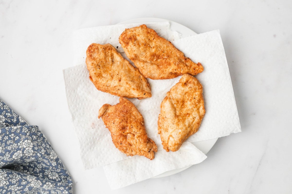 Breaded and pan fried chicken breasts sitting on a paper towel.