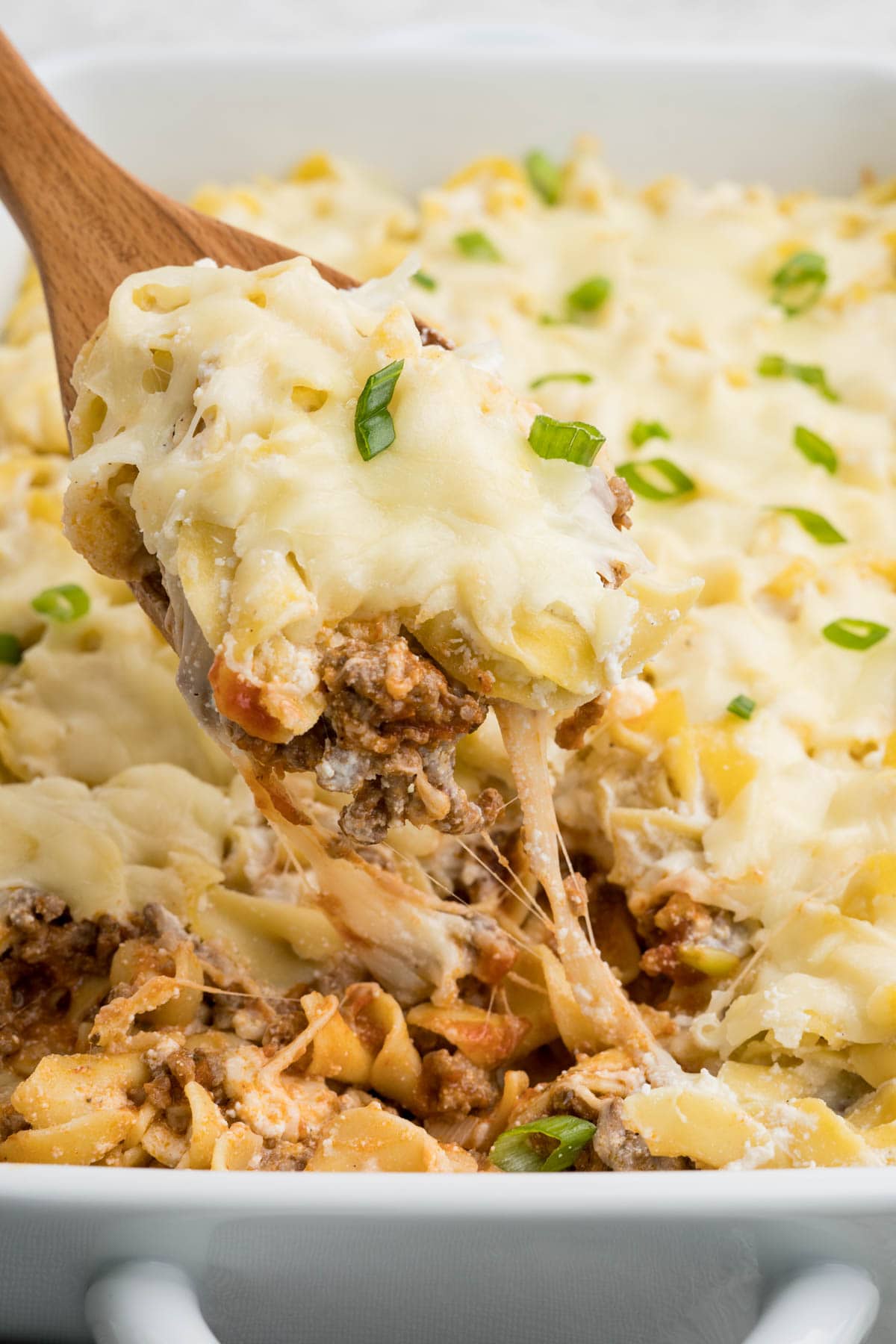 Stringy cheese from a wooden spoon with a casserole.