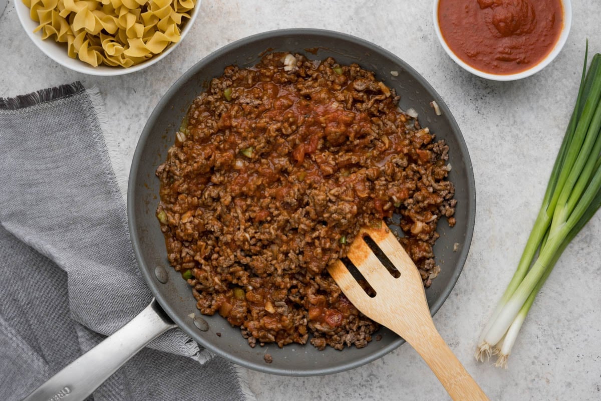 ground beef mixed with tomato sauce in a skillet.