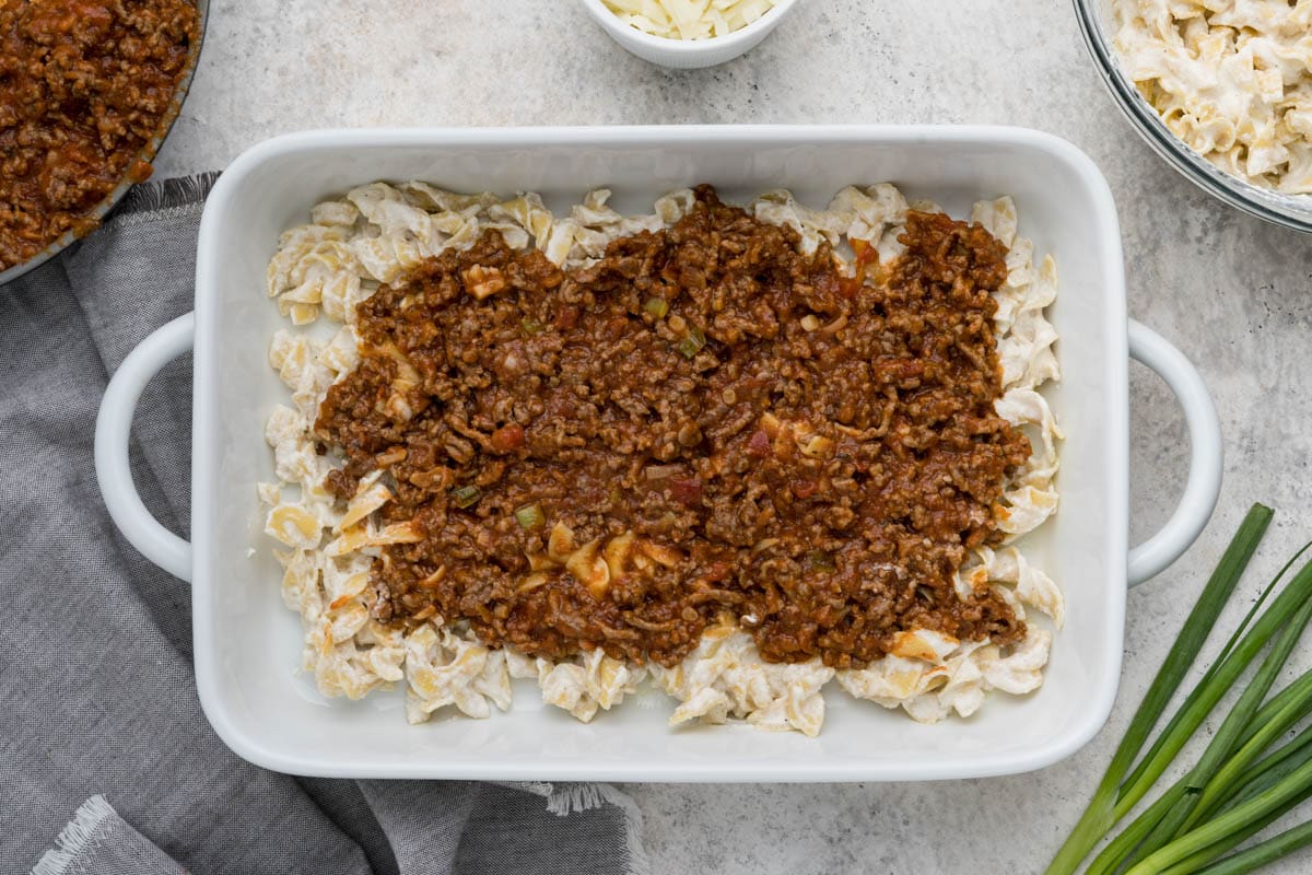 Creamy egg noodles and meat with marinara in a casserole dish.