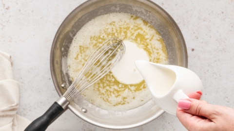 Cream being poured into a skillet with melted butter.