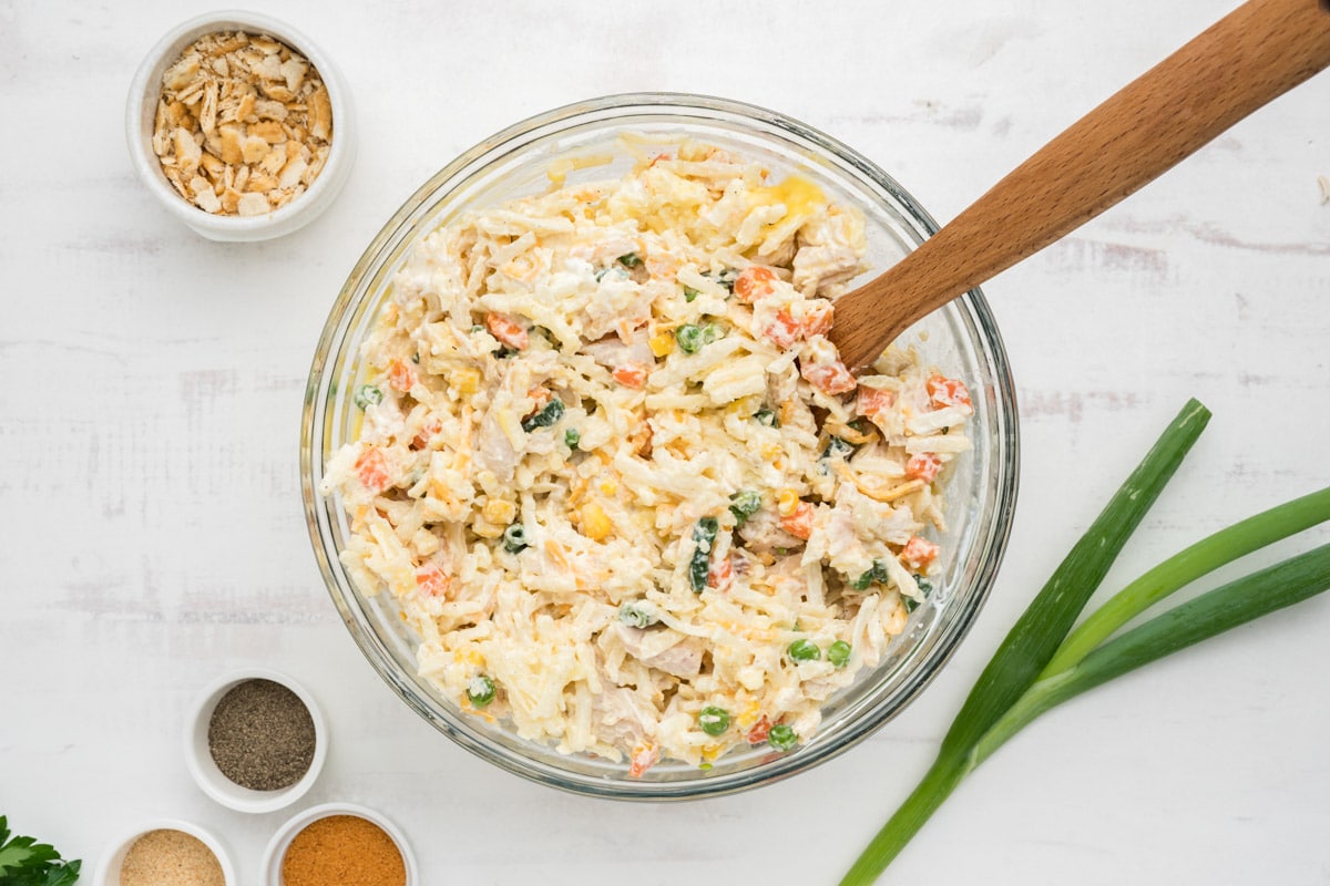 shredded chicken combined with sour cream and veggies in a large bowl.