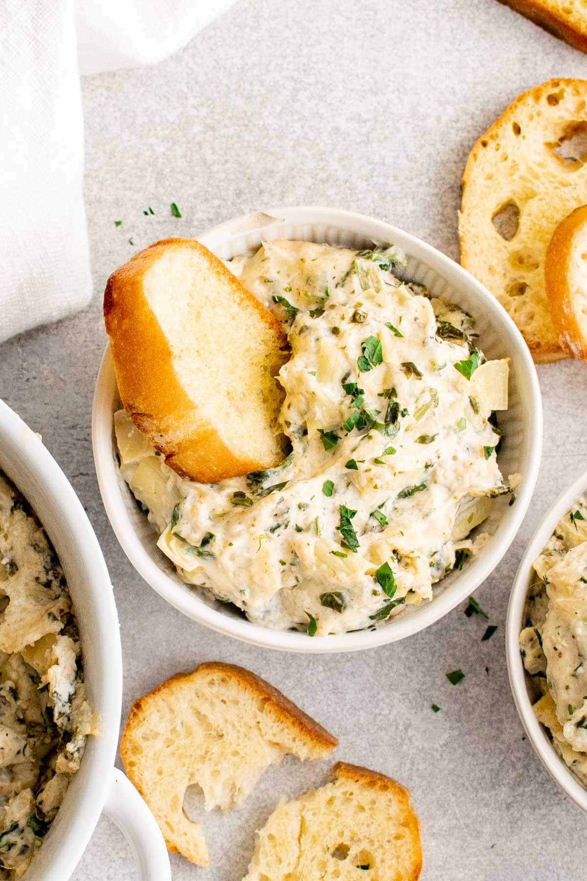 Crab spinach artichoke dip in a small dish with toasted bread. 