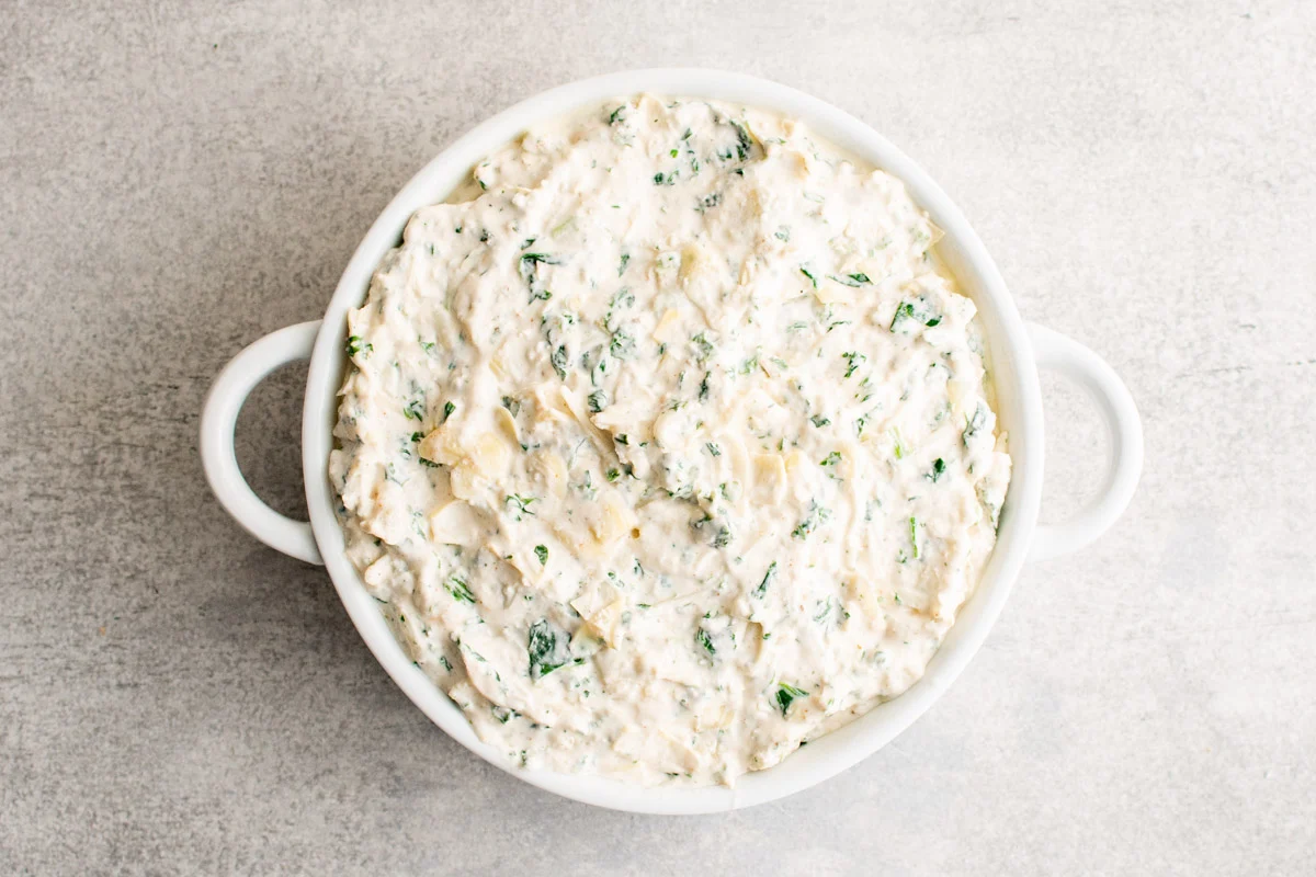 Unbaked Crab spinach dip in a baking dish. 