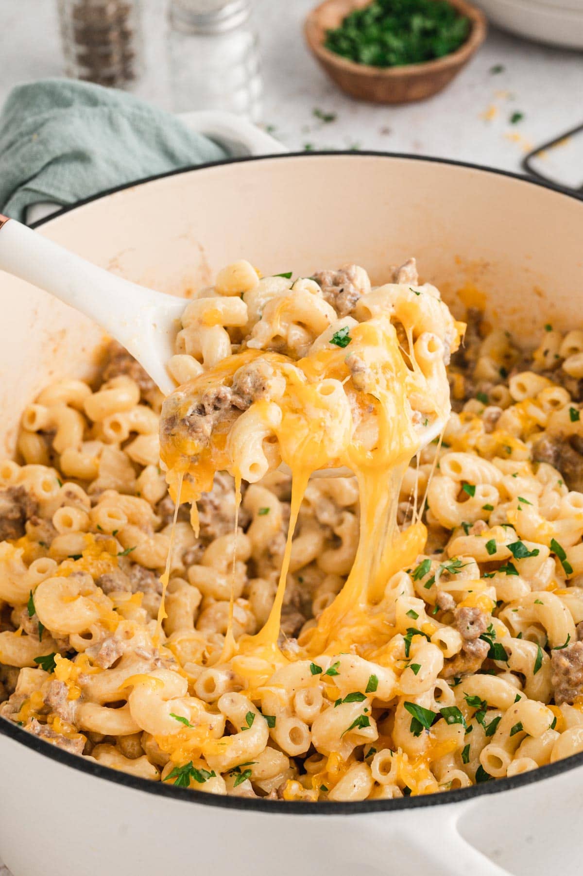 Large dutch oven soup pot with macaroni, hamburger and cheese and a wooden spoon.