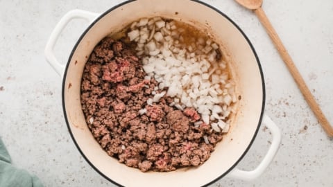 Cooked ground beef, diced onions in a dutch oven.