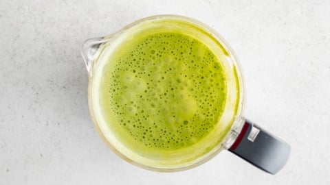 Green creamy liquid in a food processor.