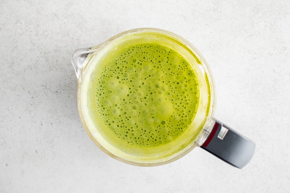 Green creamy liquid in a food processor.