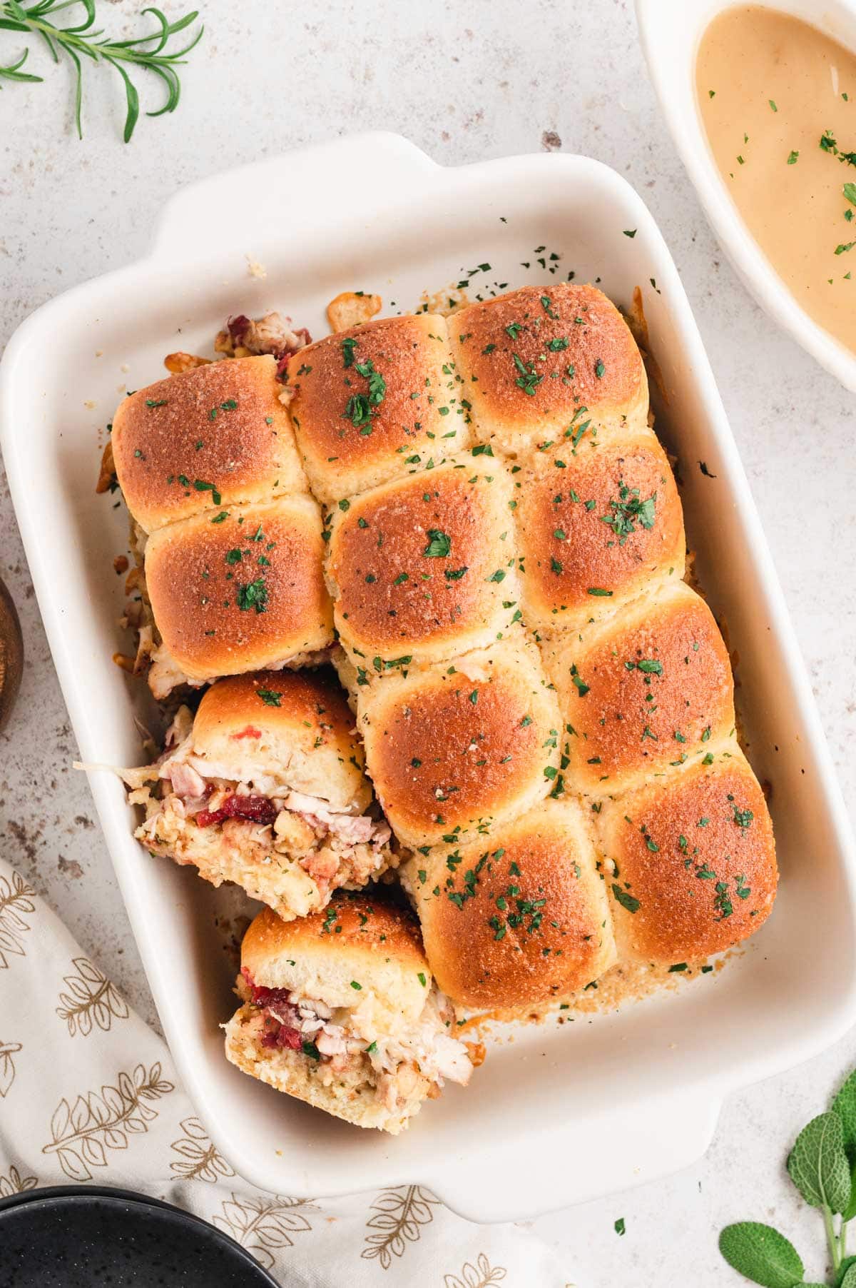 Slider rolls baked, with 2 turned on their side to reveal the turkey, stuffing and cranberry sauce filling.