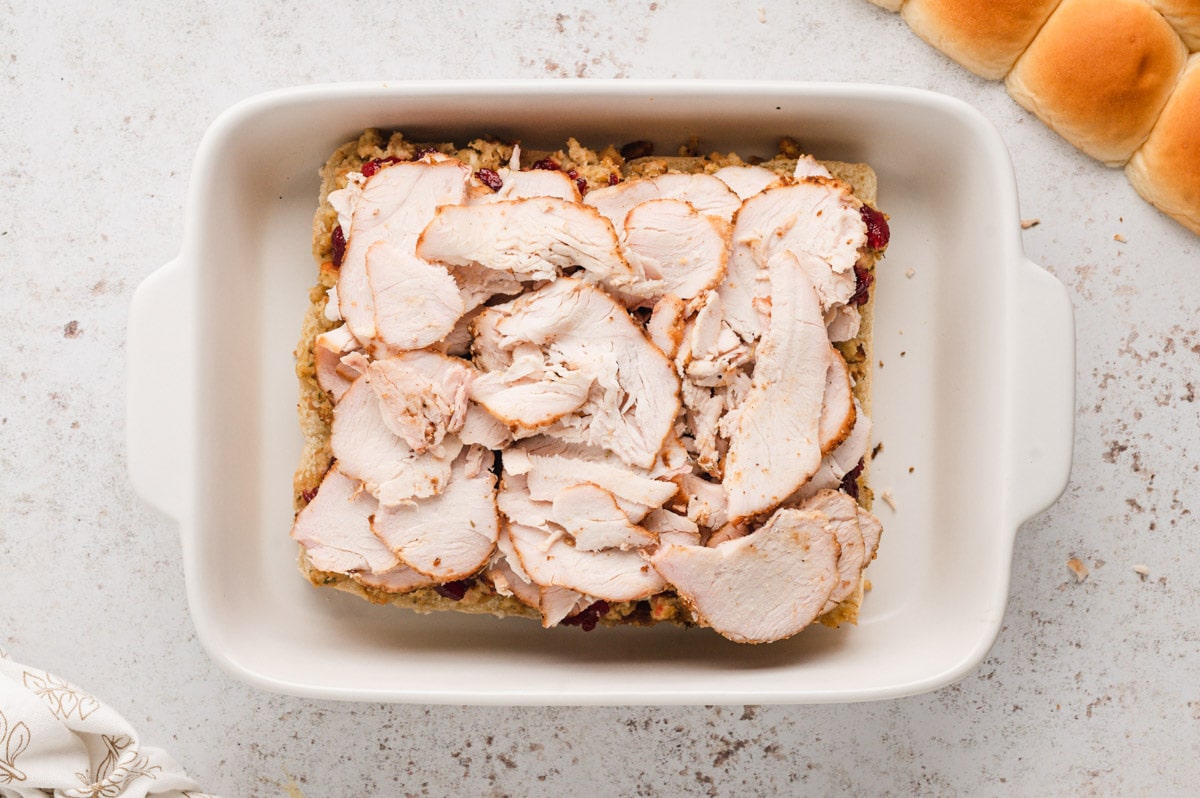 Layer of sliced turkey on rolls.