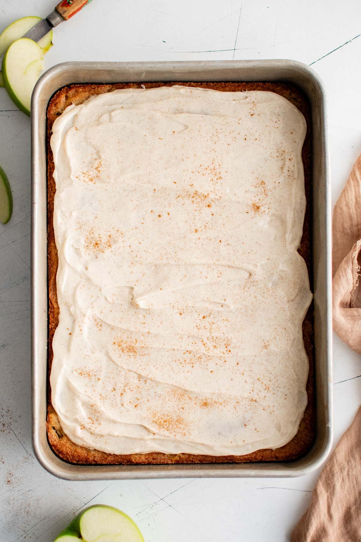Apple cake with white frosting in a cake pan.