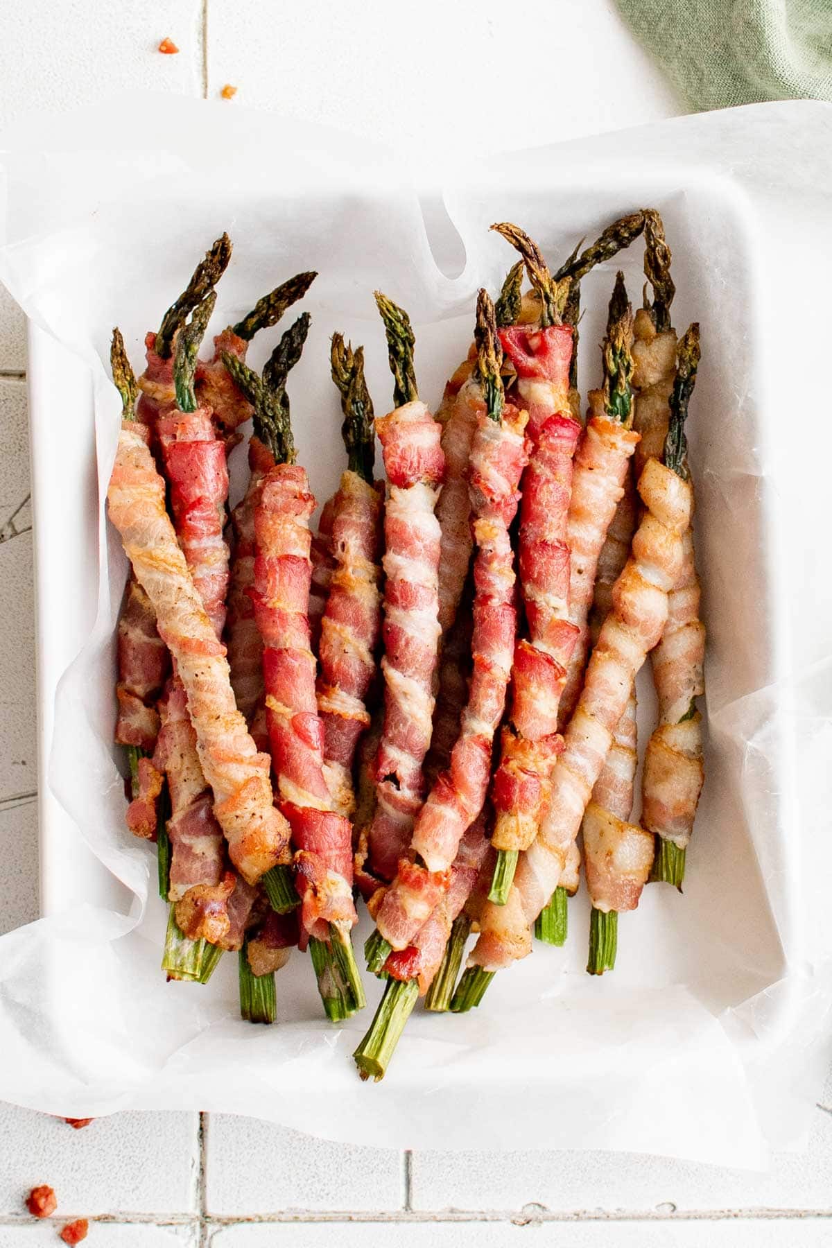 A stack of bacon wrapped asparagus in a white dish.