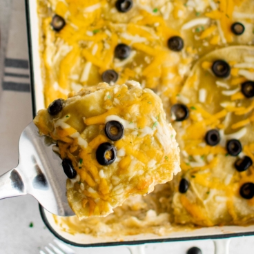 Chicken Enchilada Casserole, with a slice held up by a serving spatula.