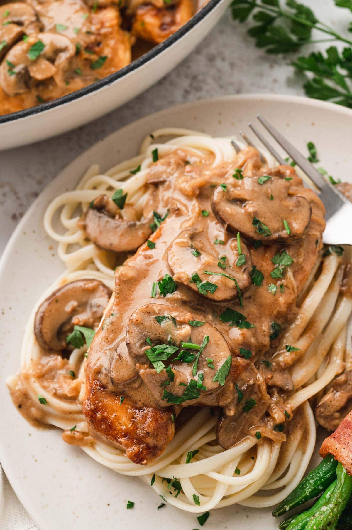 Chicken breast on a bed of noodles with a creamy mushroom sauce.