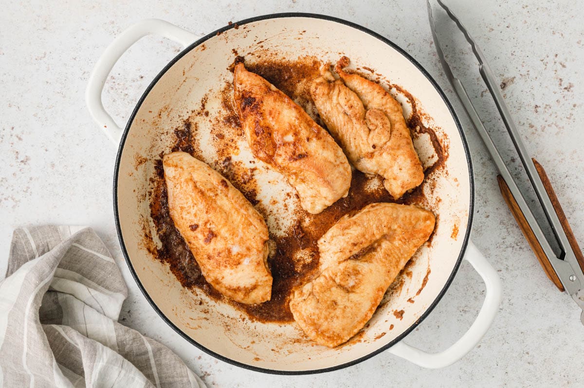 Chicken cutlets browned in a large cream colored skillet.