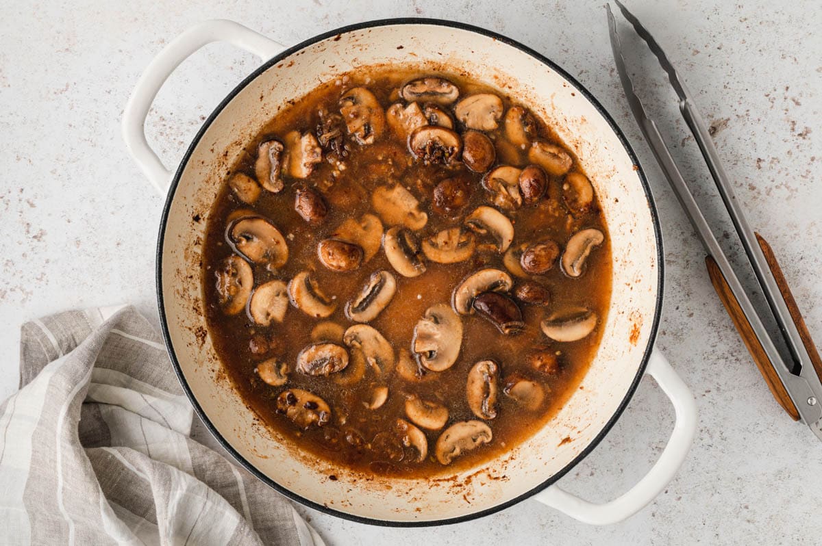 Mushrooms in a brown sauce in a skillet.
