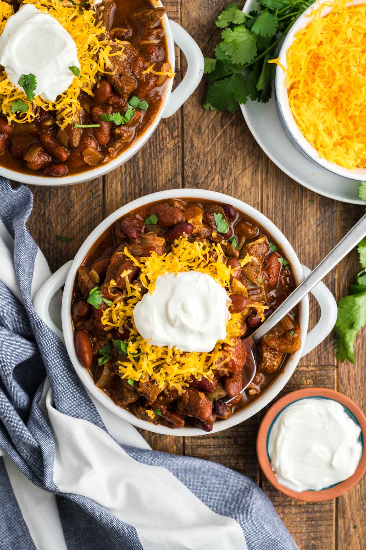 White bowls with chili topped with sour cream and cheese.