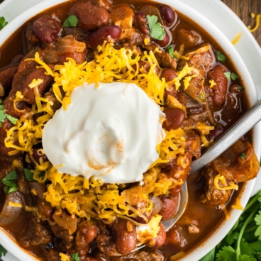 Chili with sour cream and shredded cheese topping.