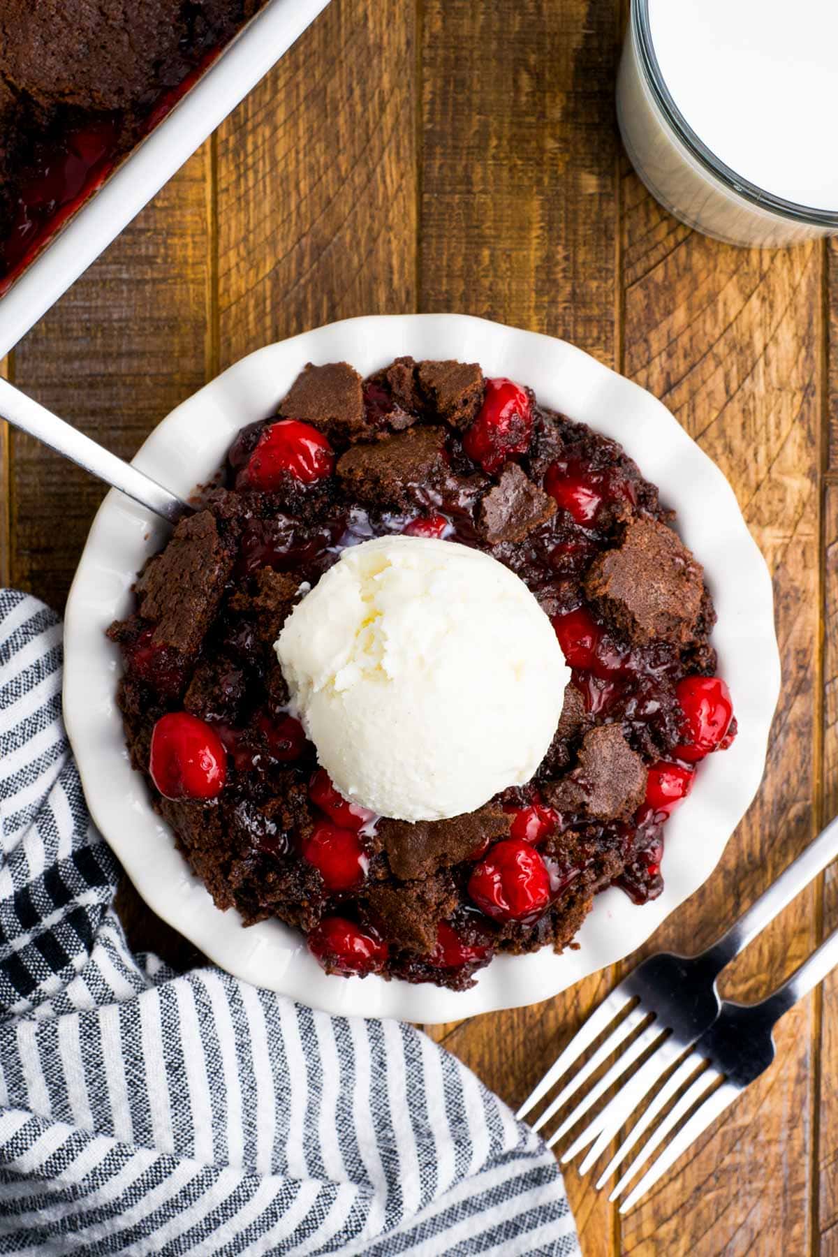 Chocolate cherry dump cake with vanilla ice cream and a spoon.