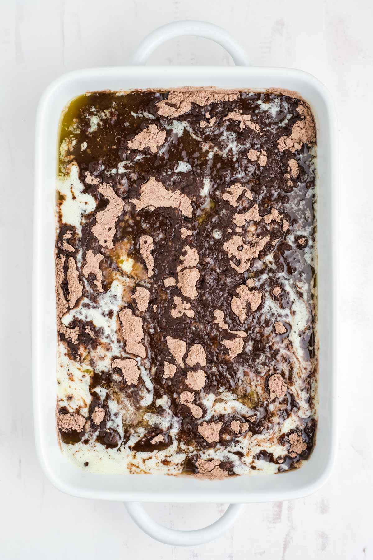 Melted butter drizzled over chocolate cake mix in a baking dish.