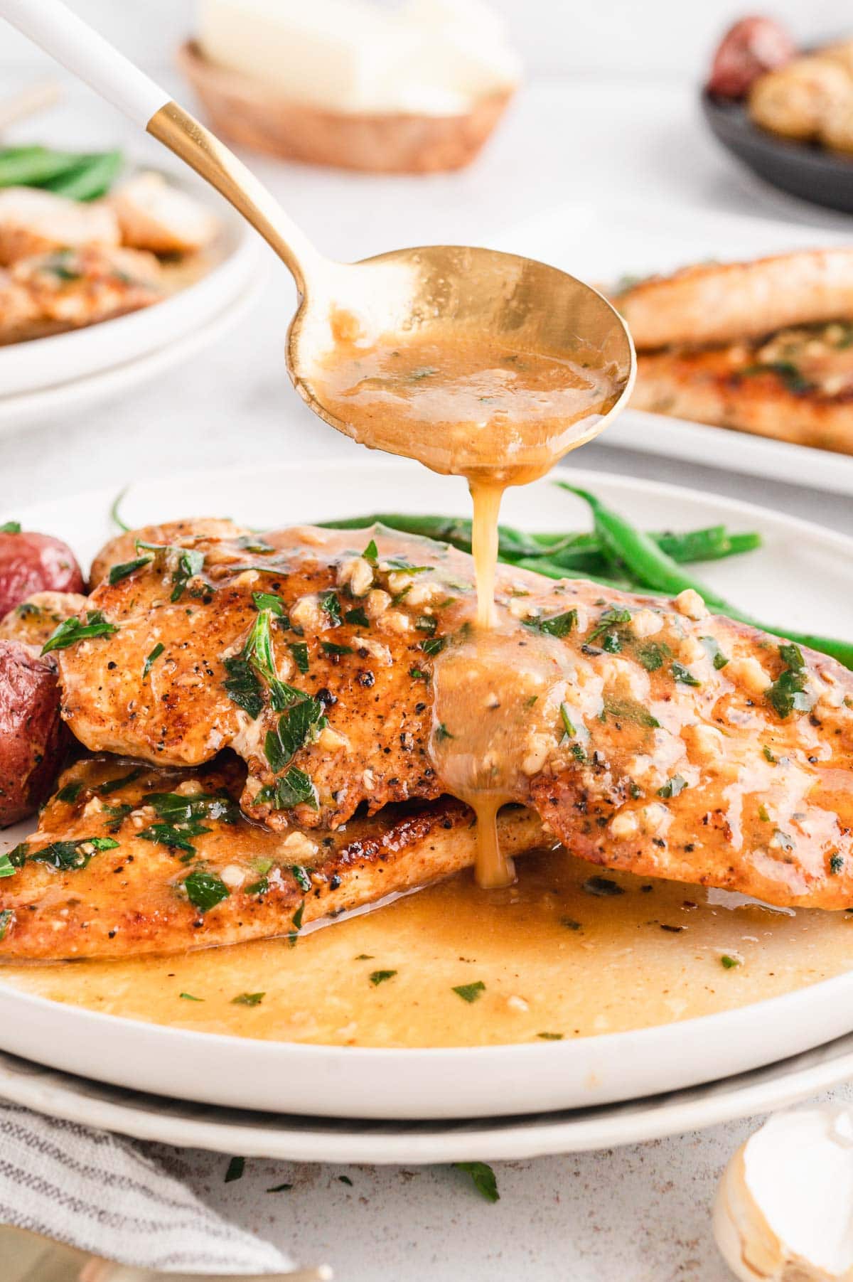 Garlic butter sauce spooned over a piece of chicken on a plate.