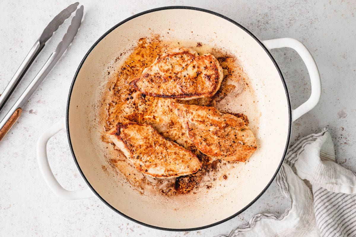 Seared chicken breasts in a large skillet.