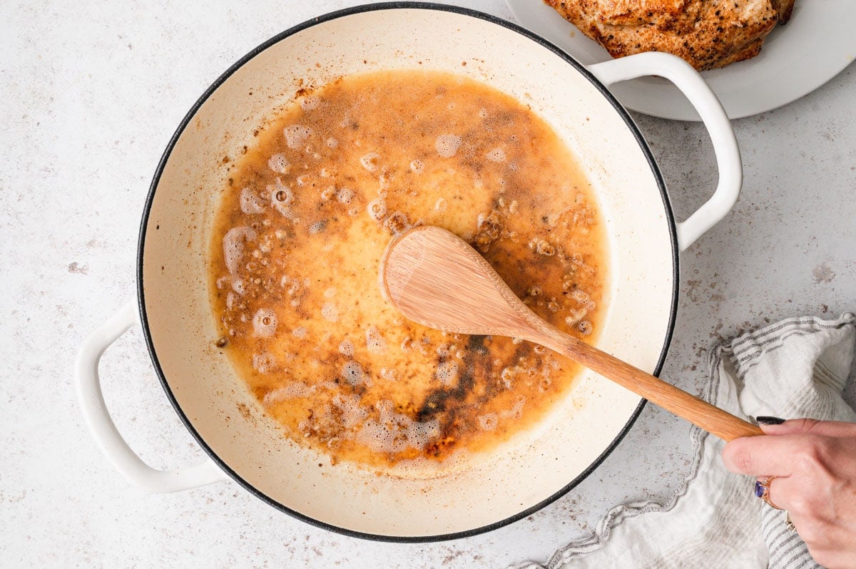 White wine added to a skillet and a wooden spoon used to scrape up browned bits.