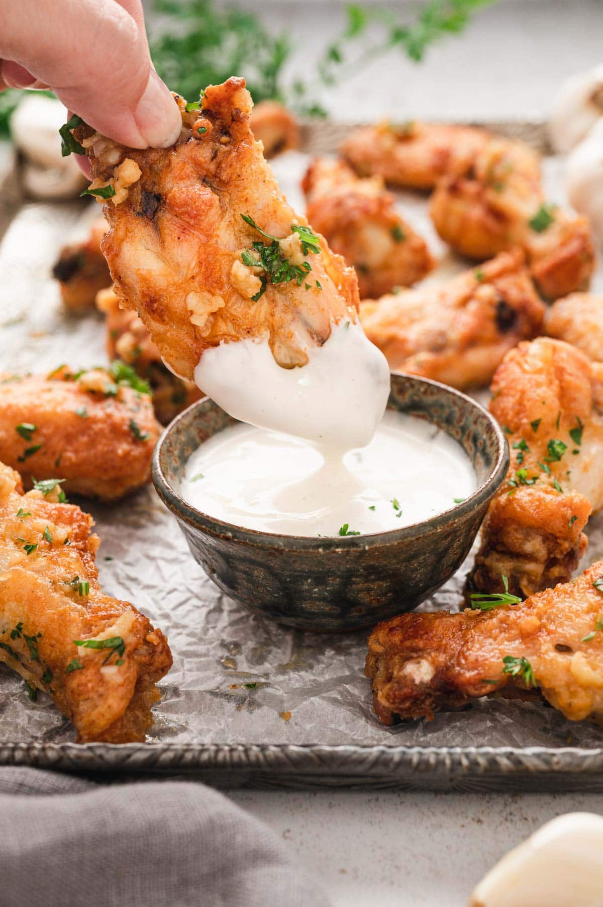 Garlic chicken wings dipped into a dish of ranch.