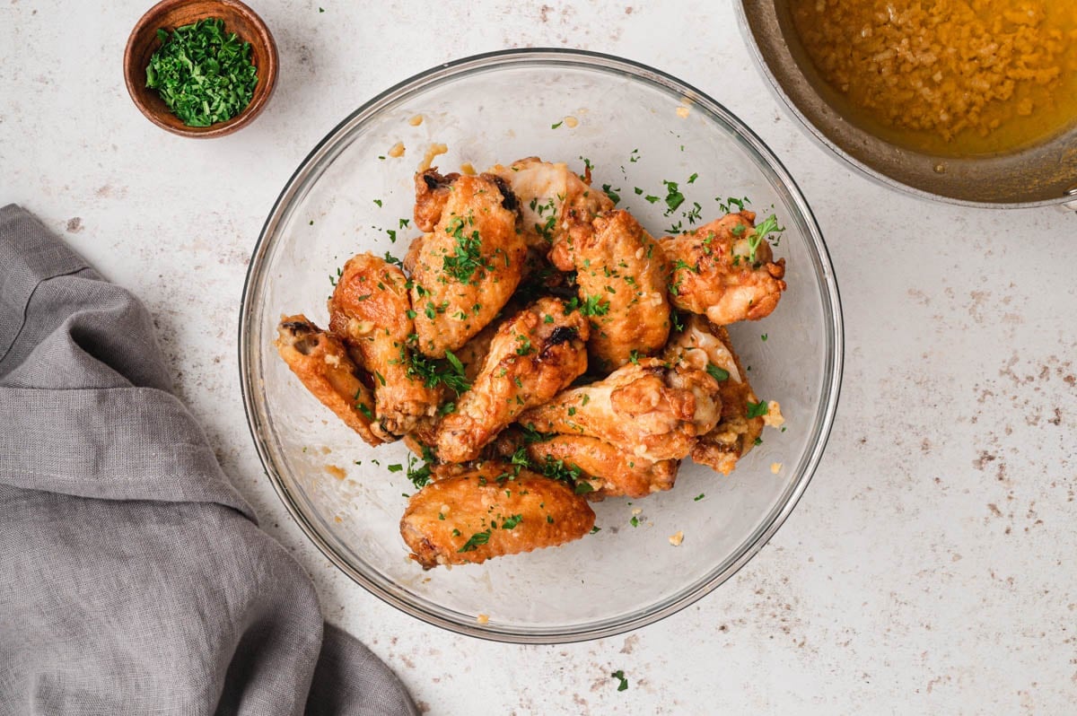 Crispy chicken wings in a bowl with garlic butter sauce.