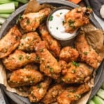 Chicken wings on a silver tray with carrot sticks and celery sticks and ranch dip.