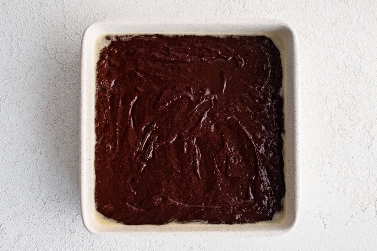 Brownie batter in a square pan.