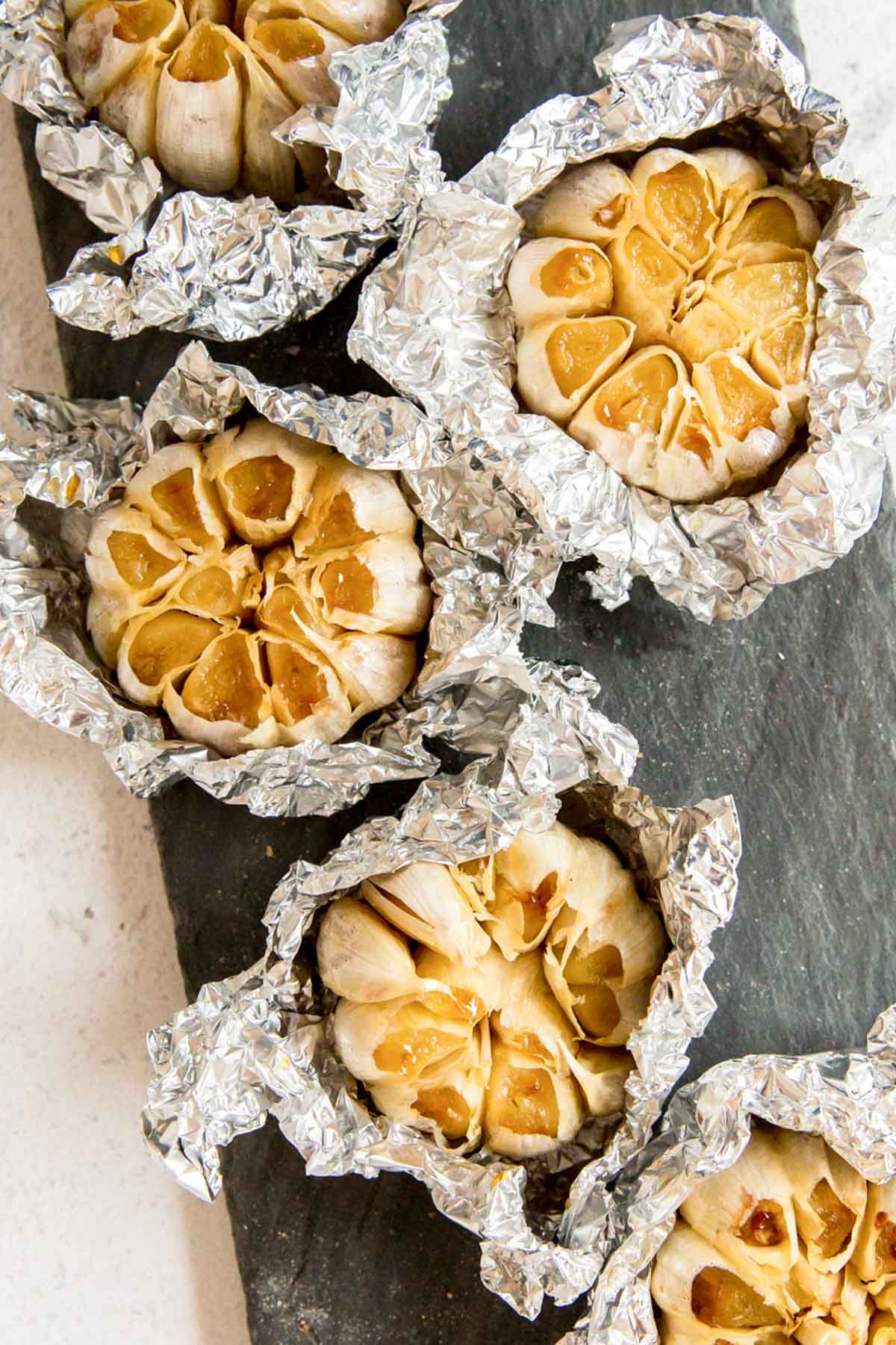 Heads of roasted garlic sitting in foil.