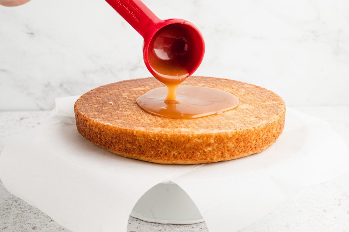 Pouring caramel sauce onto a cake.