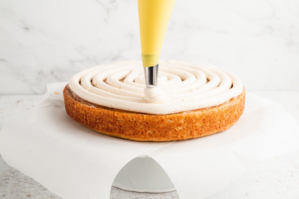 Piping icing onto the top of a cake.