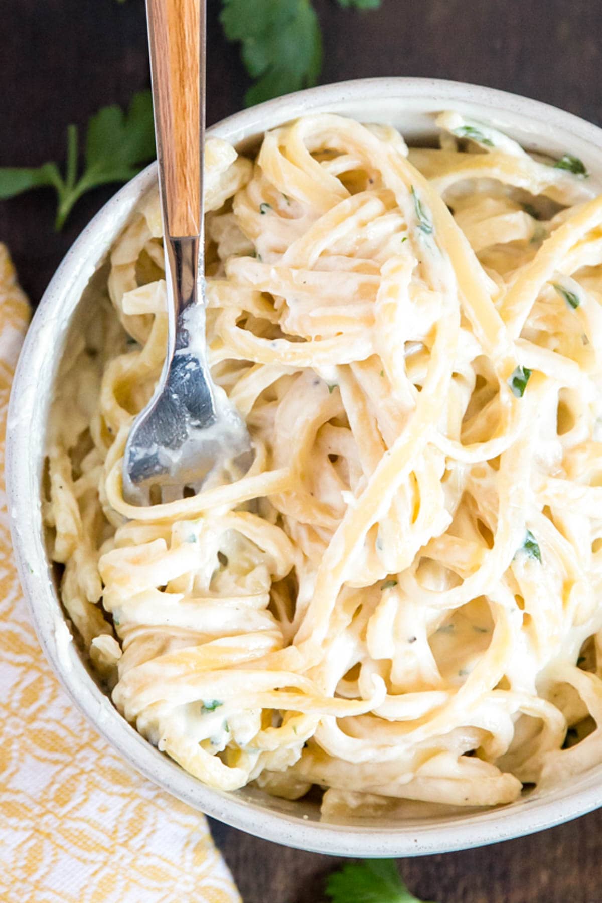 Fettuccine noodles with alfredo sauce in a small bowl with pasta twirled onto a fork.