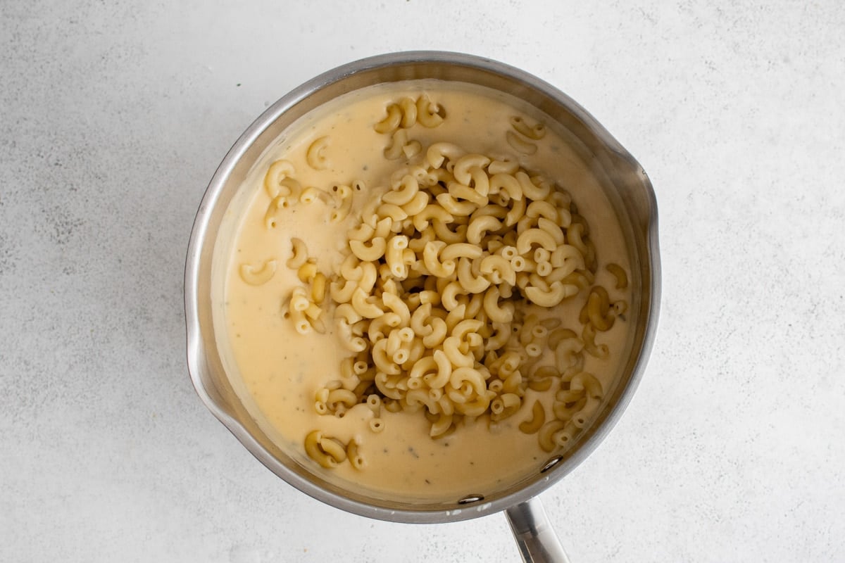 Macaroni in a saucepan of cheese sauce.