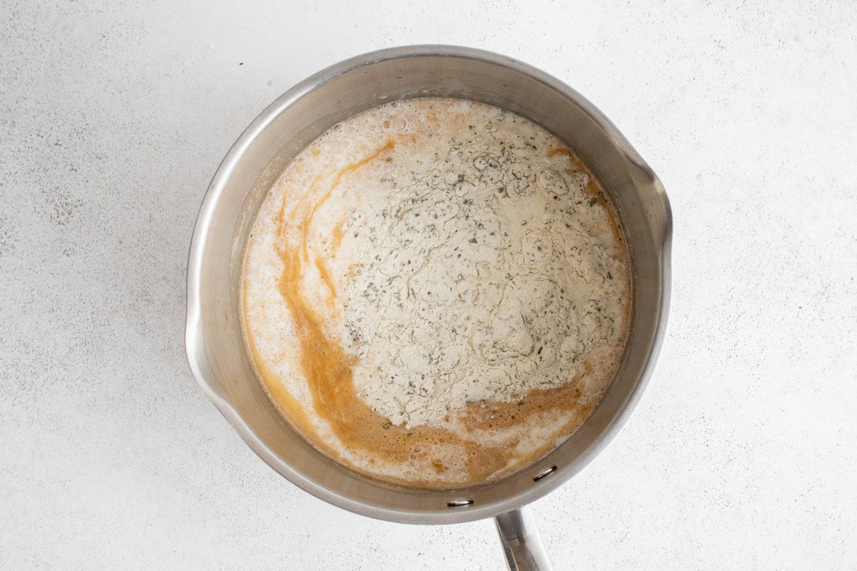 Milk and ranch seasoning added to a pot of butter and flour.