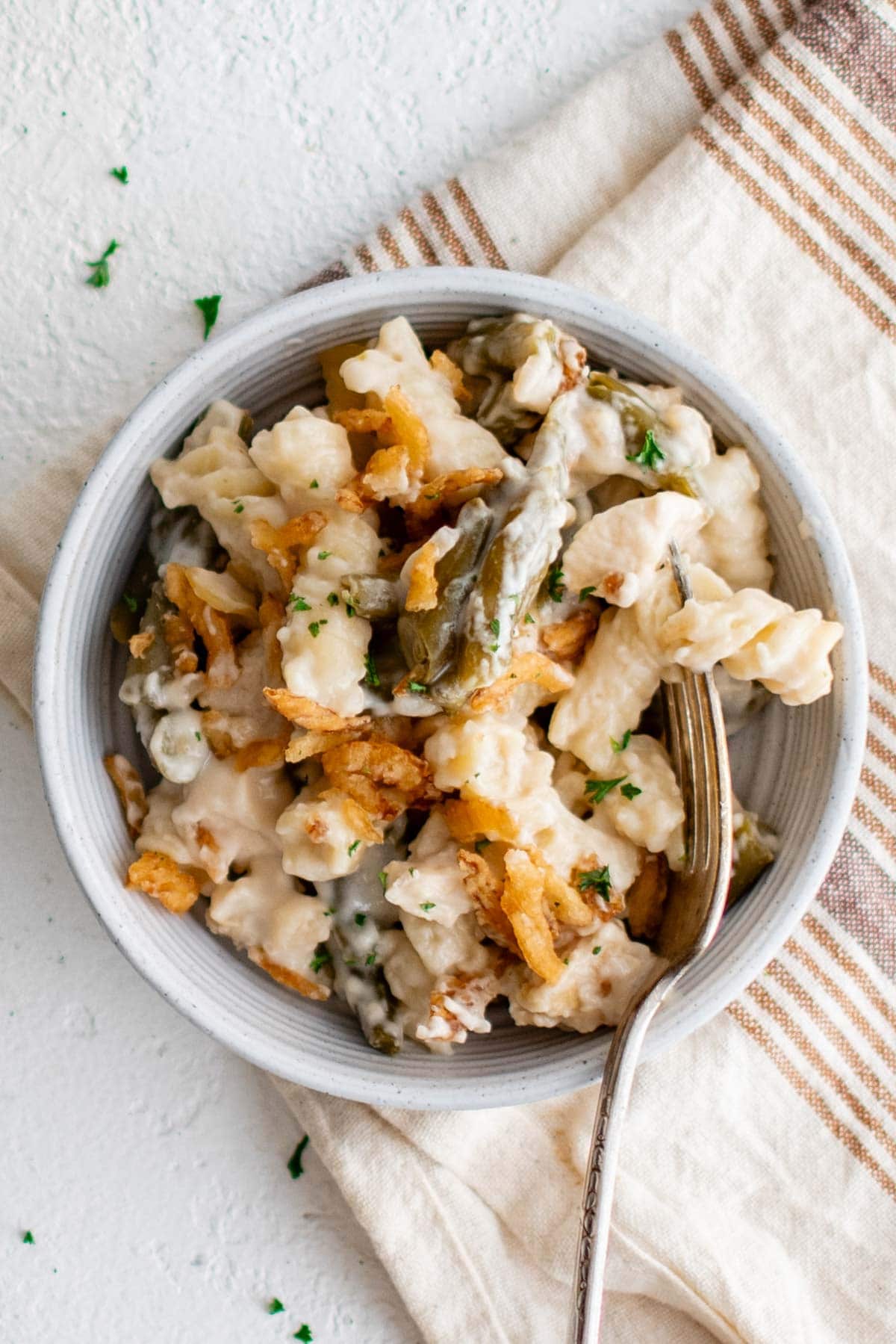 Pasta and chicken in a creamy sauce in a small bowl with a fork.