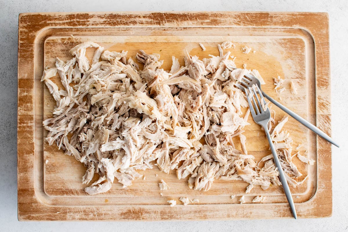 Shredded chicken on a wooden cutting board.