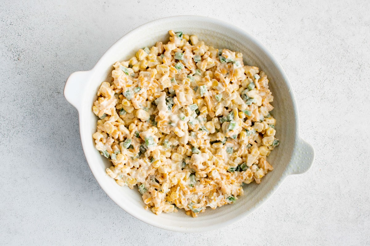 reamy corn, jalapeno and cheese mixture in a round white baking dish.