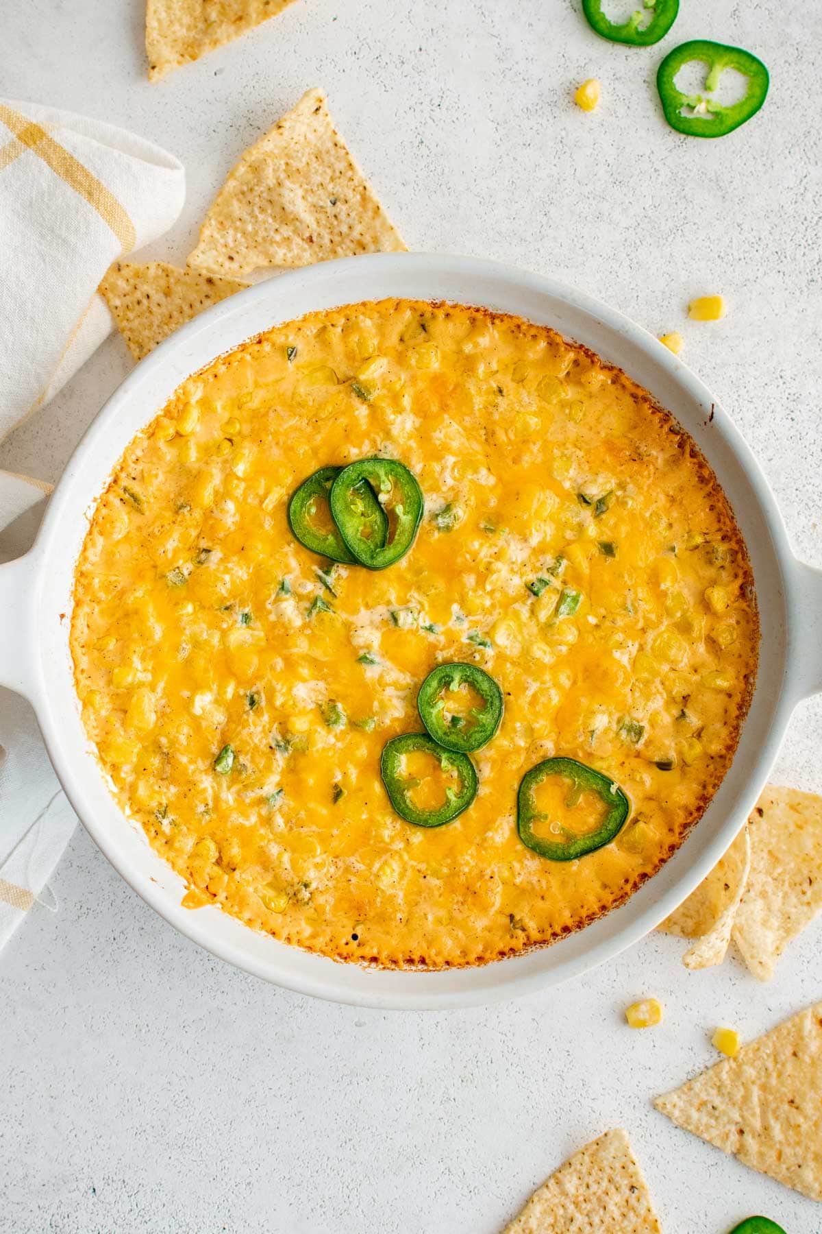 Corn casserole in a round baking dish with sliced jalapenos on top.