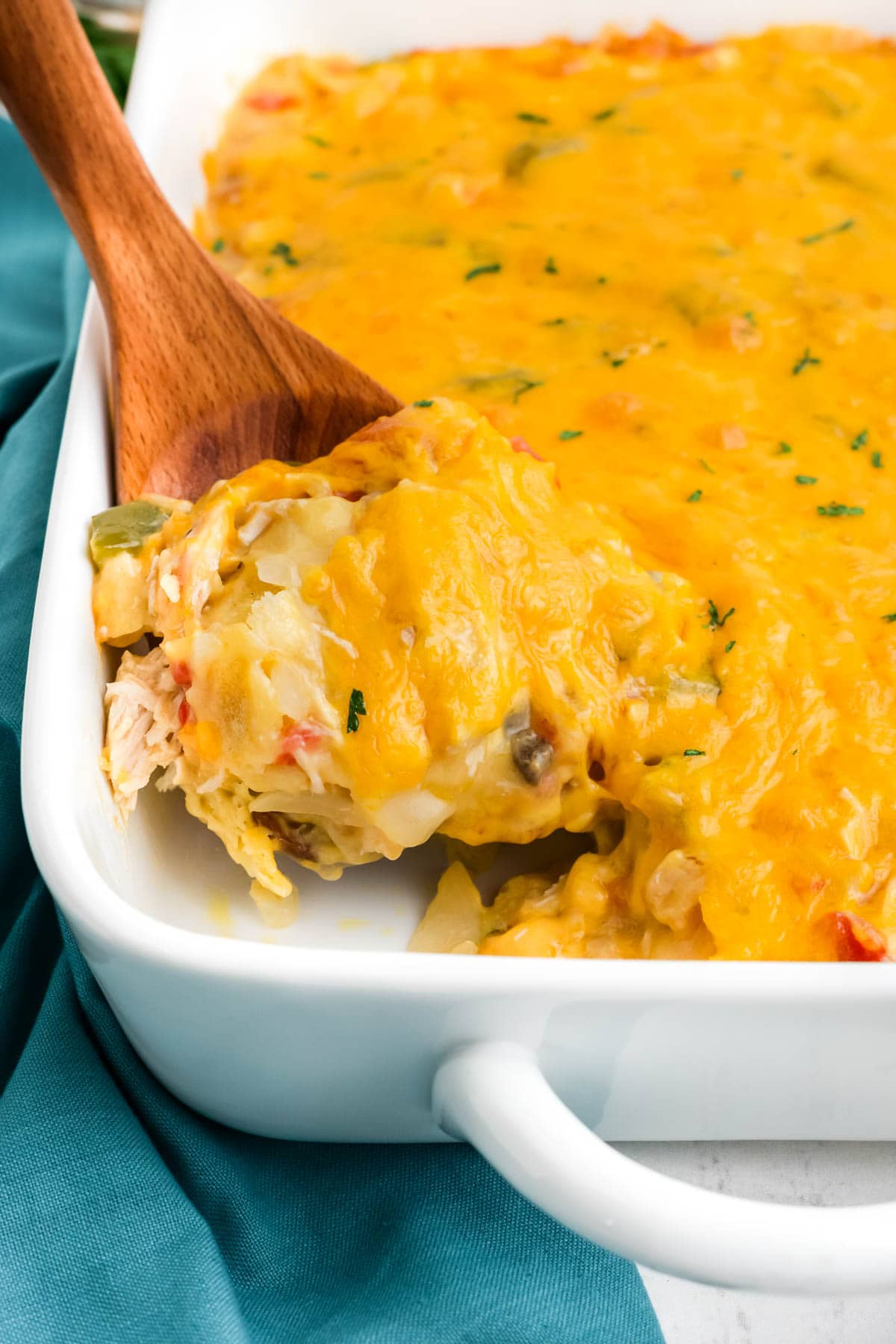 Chicken casserole with peppers in tomtaotes and cheese in a white casserole dish.
