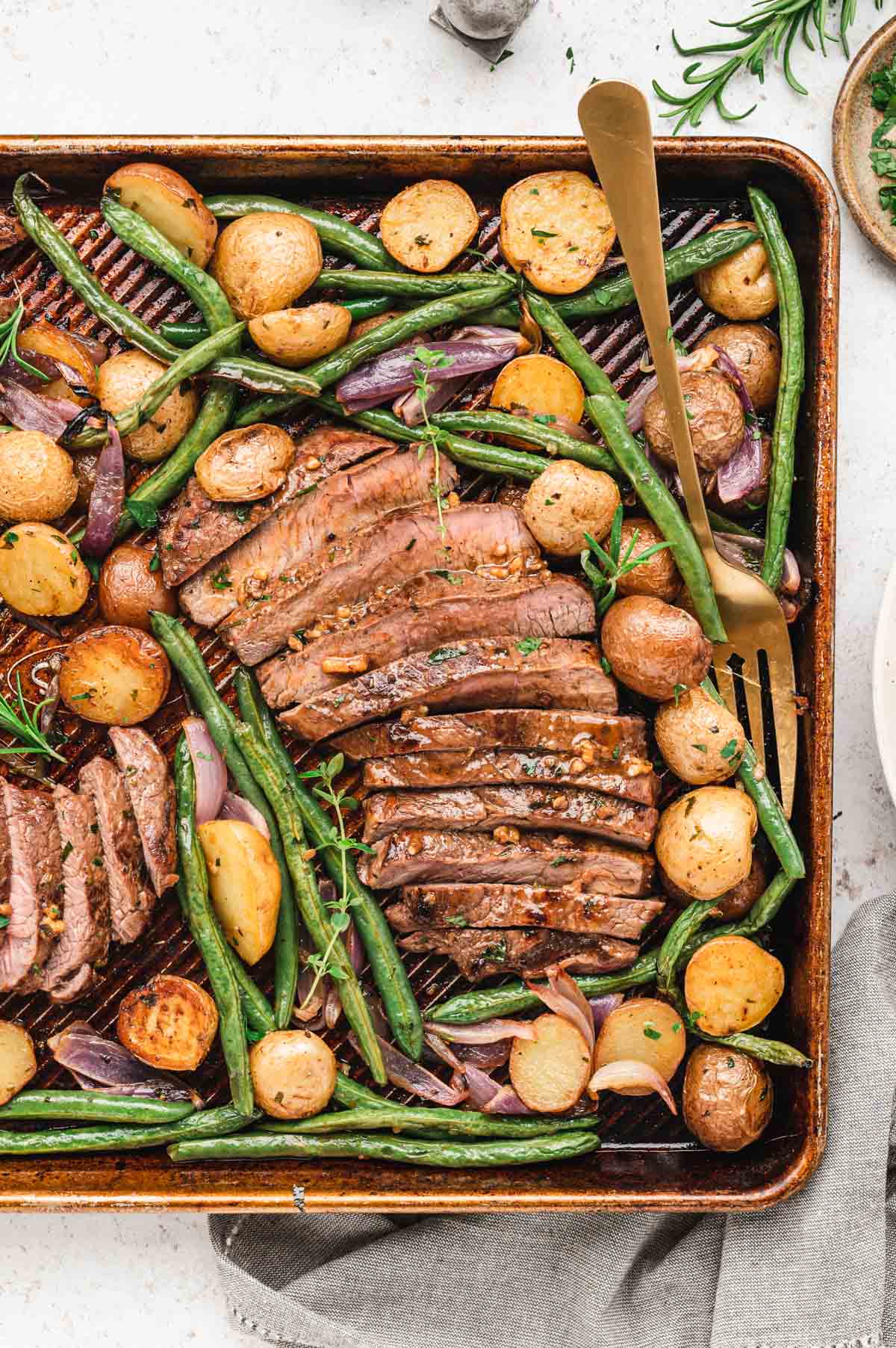 Sliced steak, green beans and potaotes on sheet pan.