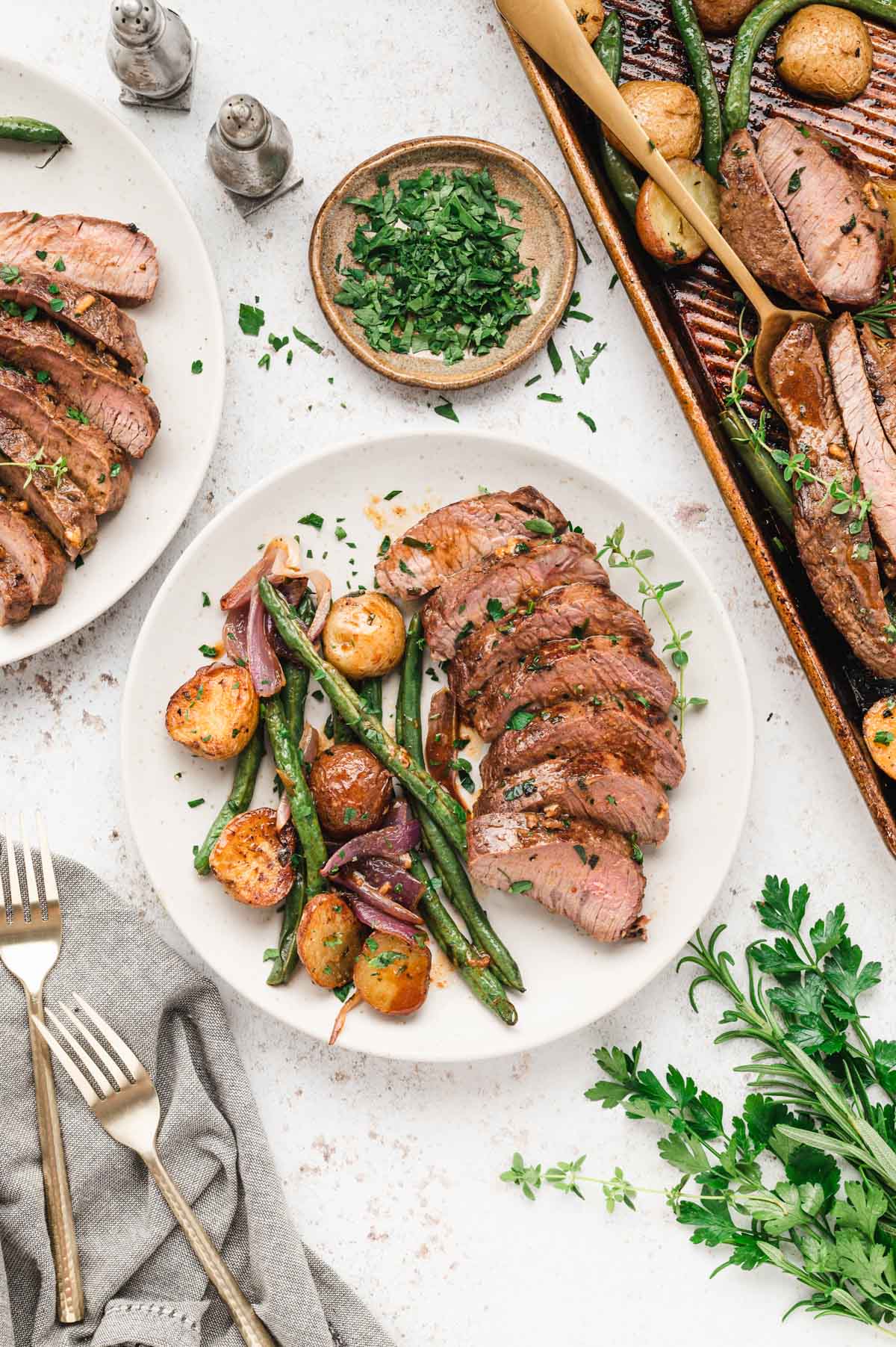 Sliced steak, green beans and potaotes on white dinner plate.