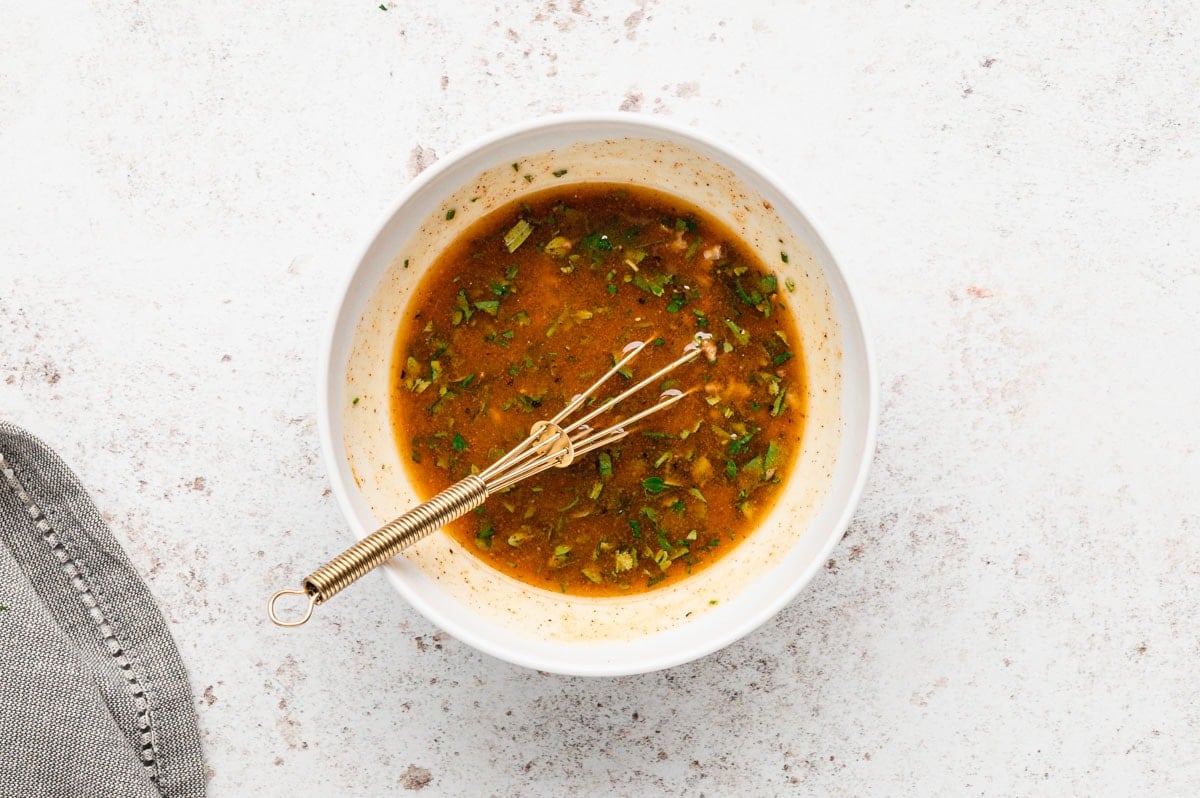 Bowl of marinade with a whisk.