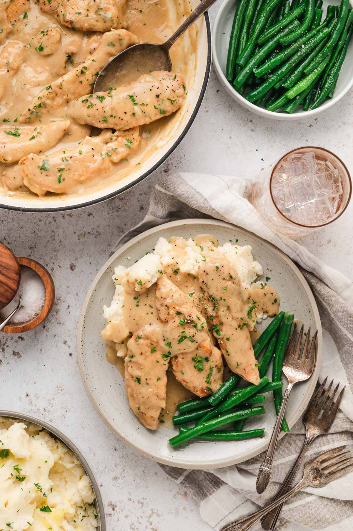 Chicken and gravy on a plate with mashed potatoes and green beans.