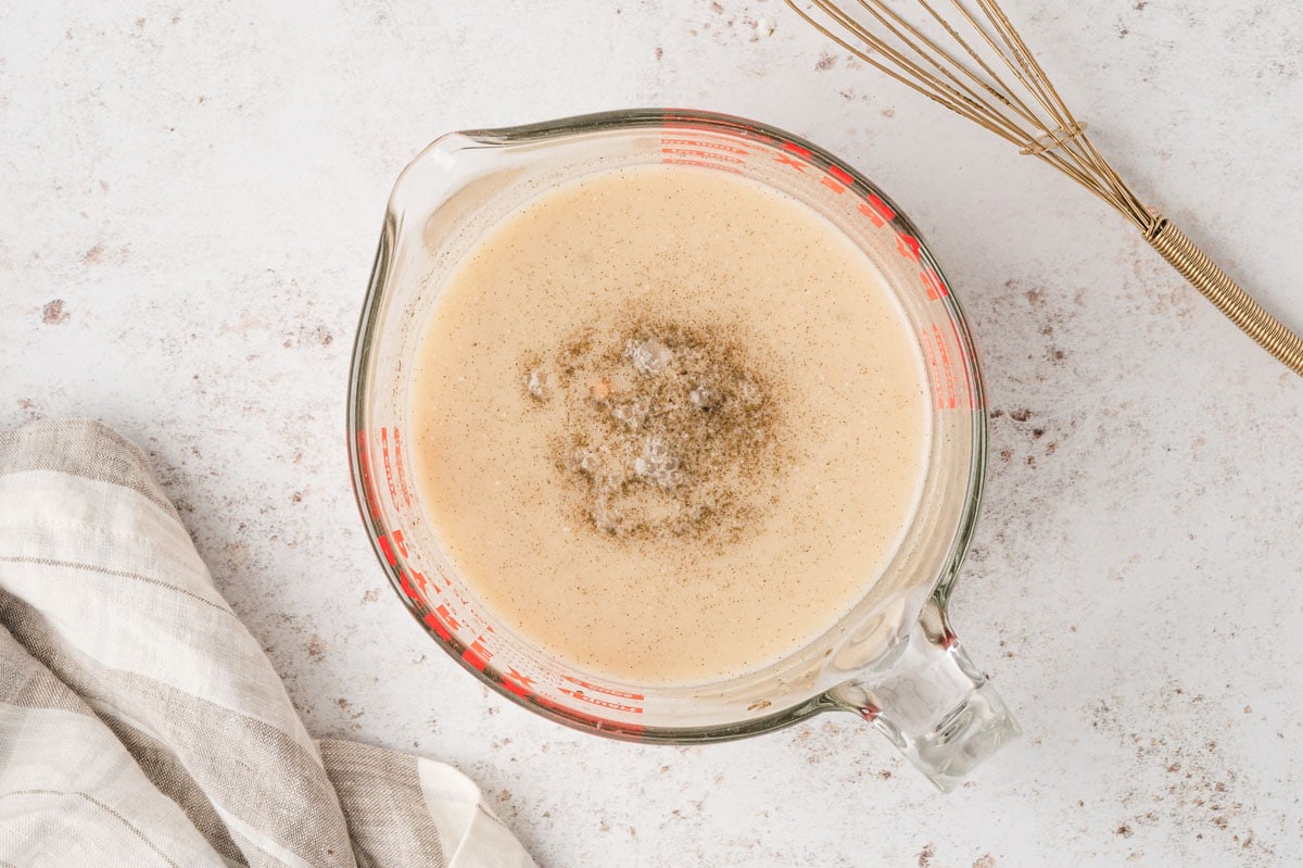 Broth gravy mixed together in a glass measuring cup.