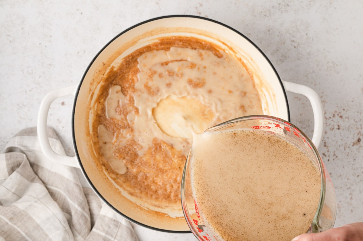 Adding broth mixture to the pan of roux.