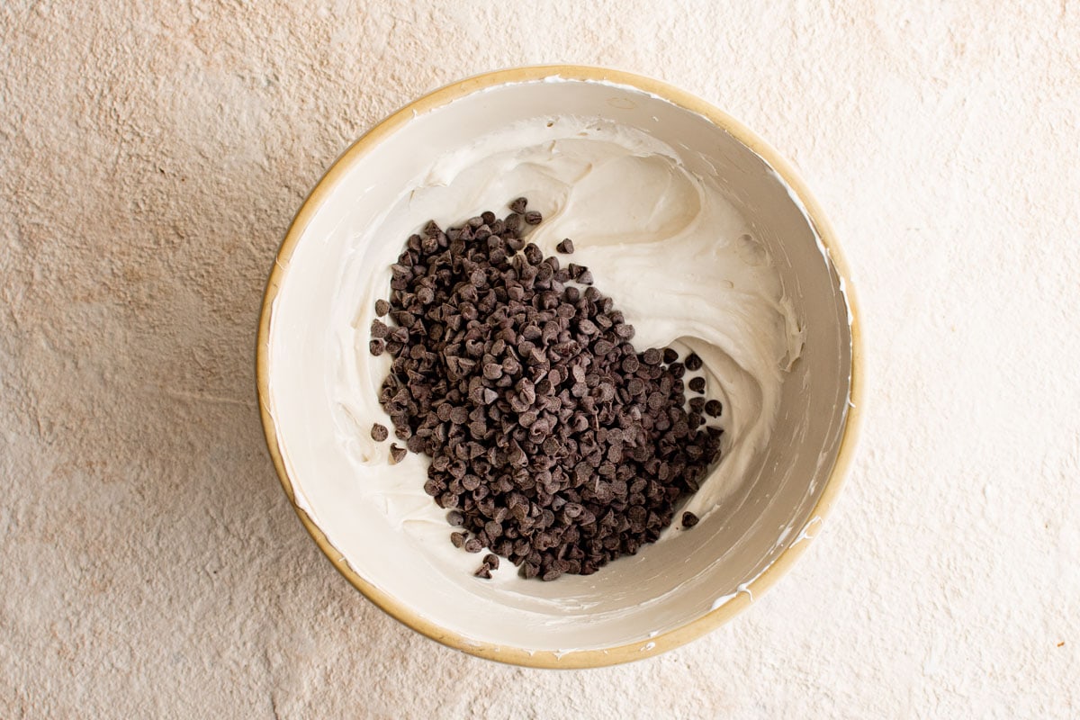 Creamy white dip mixture and mini chocolate chips in a bowl.